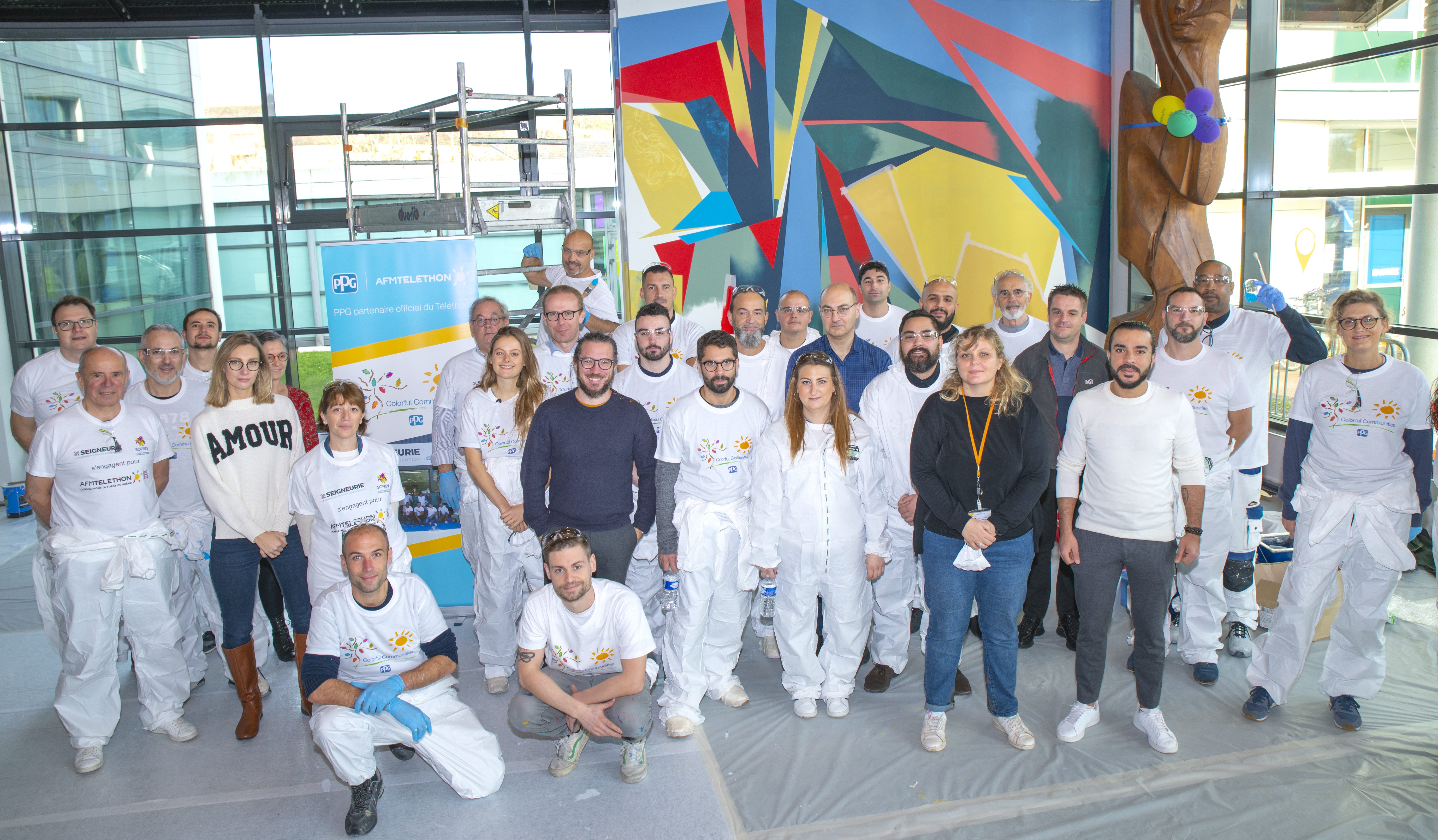 Large group of PPG volunteers posing in painting clothes in the AFM-Téléthon Géocentre in Evry, France